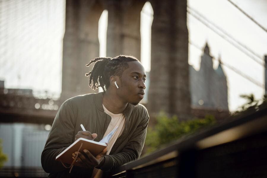 Man standing on bridge writing in his journal