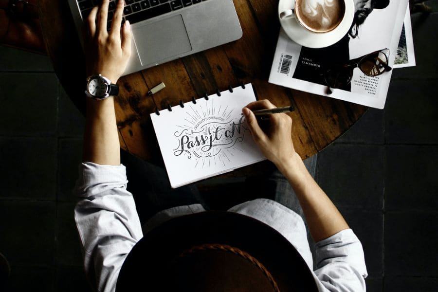 man writing in calligraphy "pass it on"